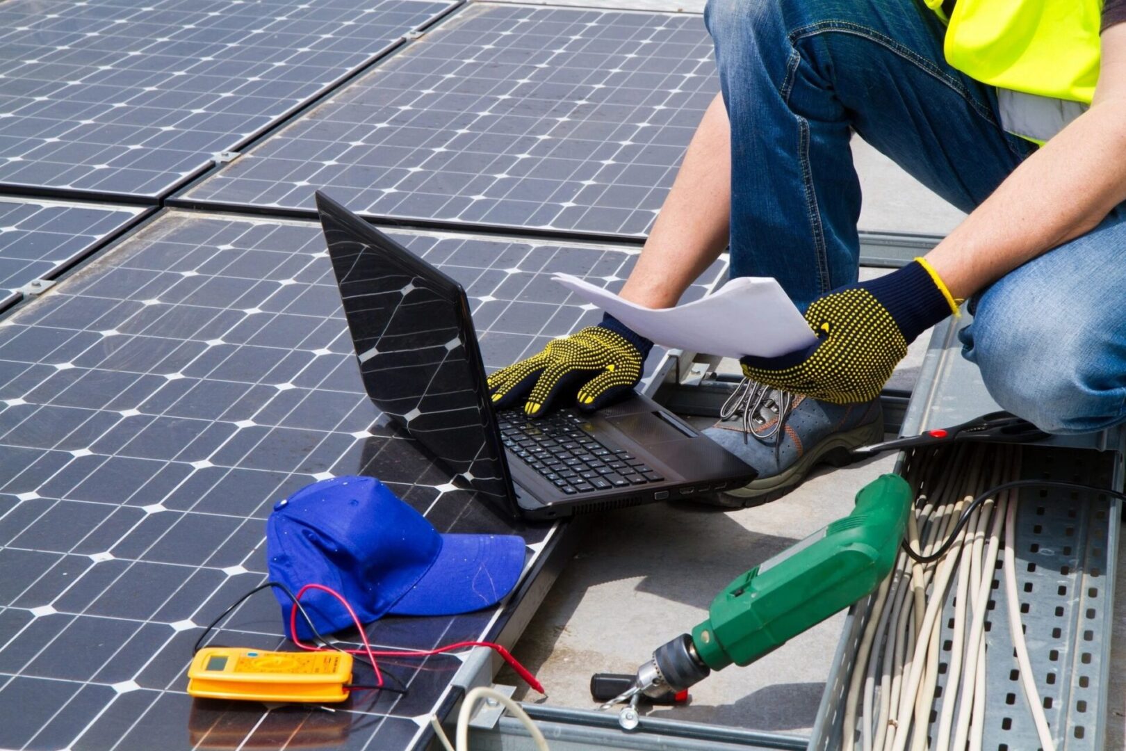 A person working on a laptop near some solar panels.